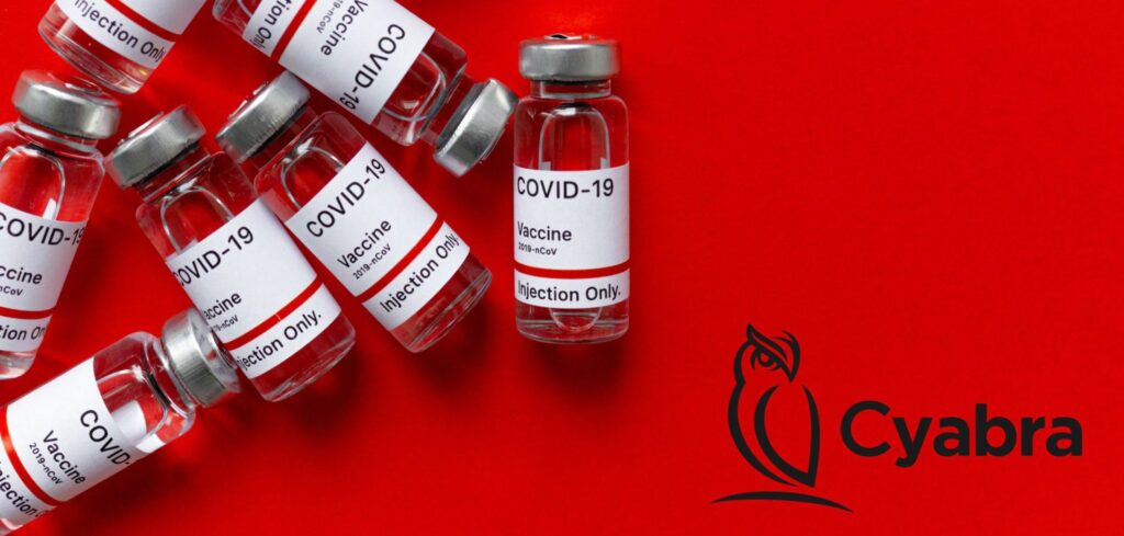 Multiple glass vials labeled “COVID-19 Vaccine” scattered on a bright red background with the Cyabra owl logo on the right