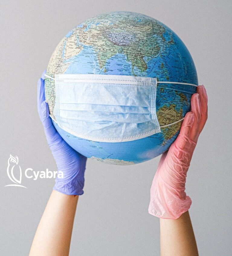 Gloved hands hold a world globe covered by a surgical mask, representing the global struggle with COVID-19 and vaccine disinformation
