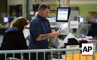 Election workers feed ballots into a tabulation machine at a midterm vote-counting center in Arizona