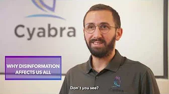 Bearded man with glasses wearing a Cyabra polo shirt standing before a Cyabra logo backdrop, accompanied by on-screen text reading 'WHY DISINFORMATION AFFECTS US ALL'