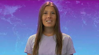 Woman with long brown hair in a light purple T-shirt speaking against a purple-to-blue world map backdrop