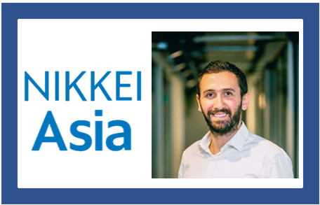 Nikkei Asia logo next to a smiling dark-haired bearded man in a white shirt standing in a corridor