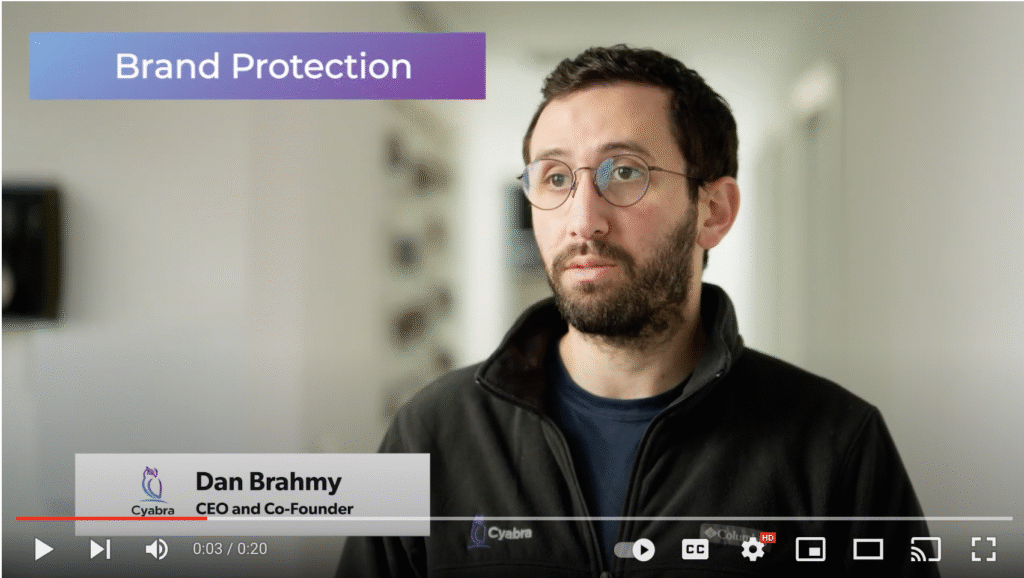 Bearded man with glasses speaking in a paused video titled Brand Protection, with lower-third caption and YouTube controls visible