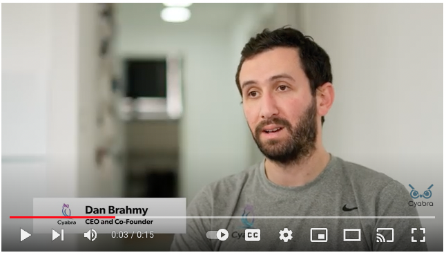 Man in a gray T-shirt speaks during a Cyabra-branded office interview, displayed as a video thumbnail with playback controls
