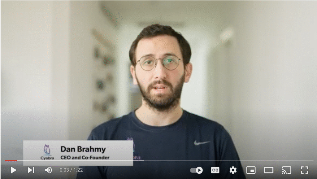 Man with glasses speaking on camera against blurred hallway background with on-screen title showing CEO and Co-Founder