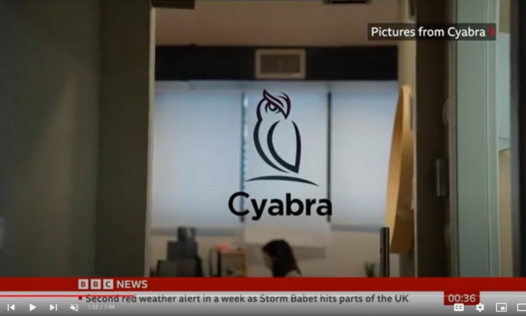 Cyabra owl logo on a glass door in an office, with a blurred employee at a desk and BBC News banner at the bottom of the video frame
