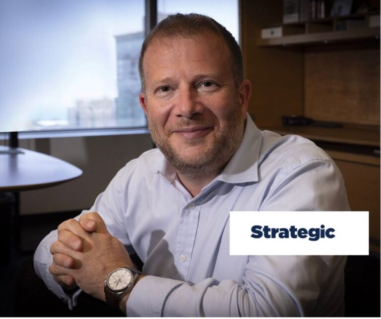 Business professional seated in an office, smiling with hands clasped, illustrating Cyabra and Golin partnership on disinformation and brand protection