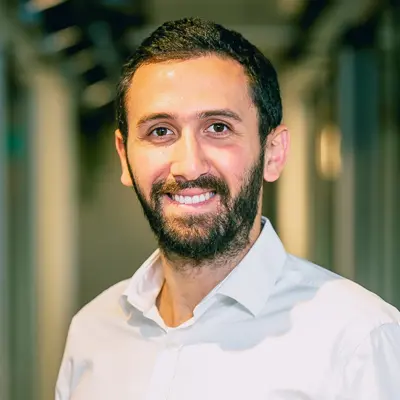 Smiling bearded man in a white dress shirt standing in a hallway
