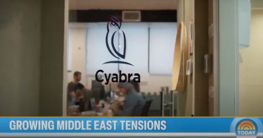 Cyabra office interior visible through a glass door bearing the company owl logo, with NBC Today banner reading “GROWING MIDDLE EAST TENSIONS” across the bottom