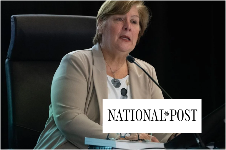 Woman in beige blazer speaking into a microphone at a hearing with National Post logo superimposed