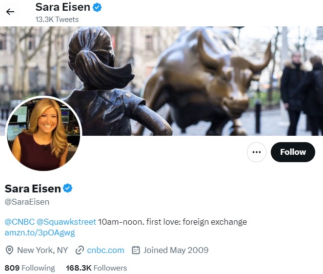 X social media profile of a verified user, showing a smiling woman’s profile photo and a header image of the Fearless Girl statue facing the Charging Bull in a city street